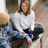 Man and woman sitting on wooden bench while holding Klean Kenteen TKWide insulated bottle with straw cap