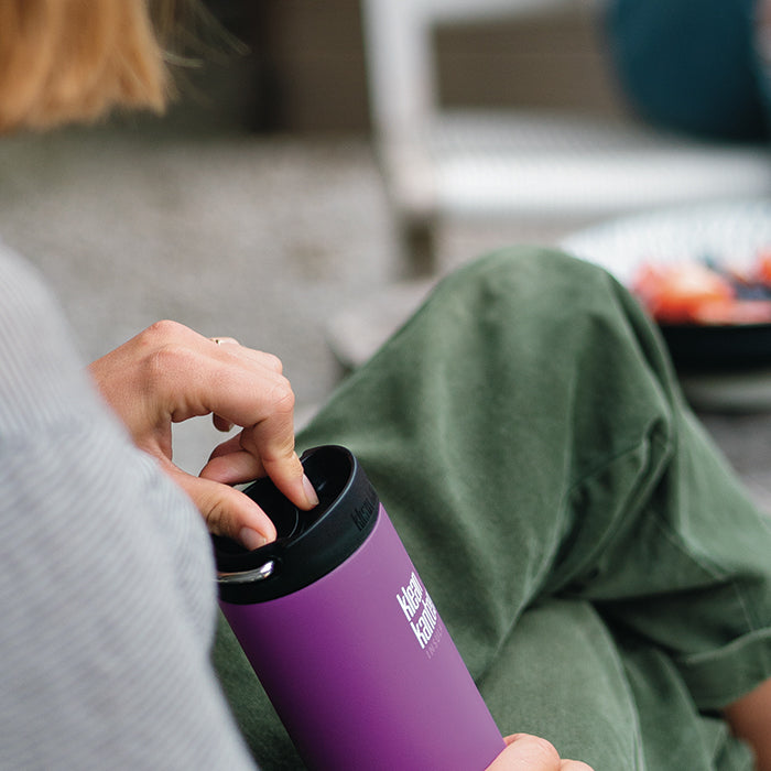 Woman crossing legs on couch holding Klean Kanteen TKWide insulated bottle with cafe cap